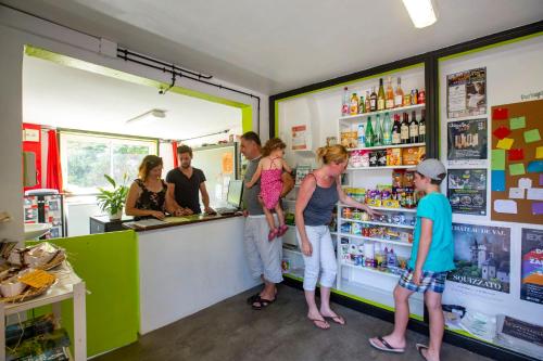 a group of people standing at a counter in a store at Camping du Lac in Marcillac-la-Croisille