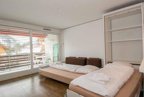 a bedroom with two beds and a large window at Ferienwohnung Studio Selvea in Adelboden