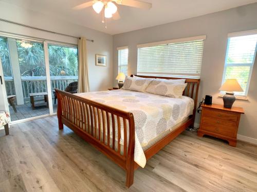 a bedroom with a bed with a wooden floor and windows at Endless Summer, North Captiva Island in North Captiva