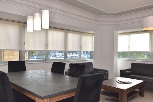 a dining room with a table and chairs and windows at 2 Bedroom, Central and Spacious Apartment with Sea View - 2 in Msida