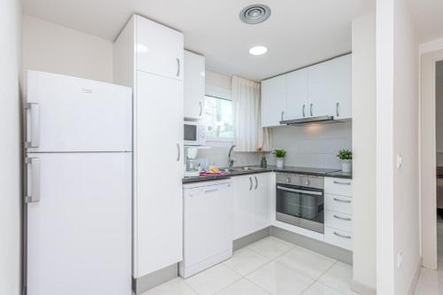 eine Küche mit weißen Schränken und einem Kühlschrank in der Unterkunft Apart-rent Apartamento Francesc Macia 1º 2001 in Roses