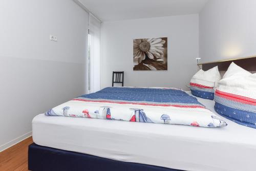 a white bed with a blue and white comforter at Ferienwohnungen MARENOR in Bensersiel