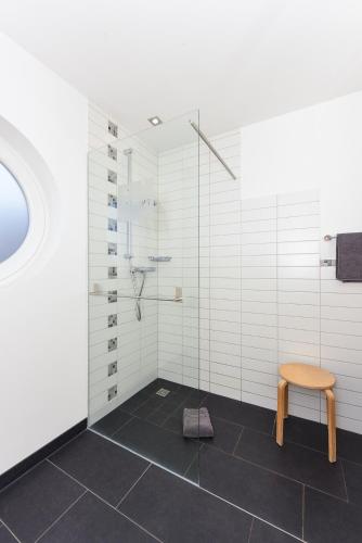 a bathroom with a shower and a wooden stool at Ferienwohnungen MARENOR in Bensersiel