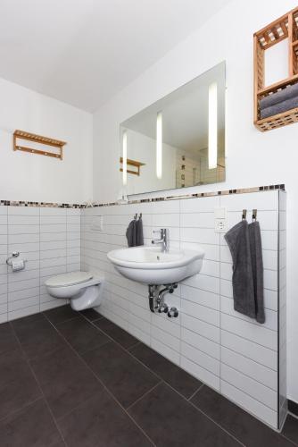 a bathroom with a sink and a toilet and a mirror at Ferienwohnungen MARENOR in Bensersiel