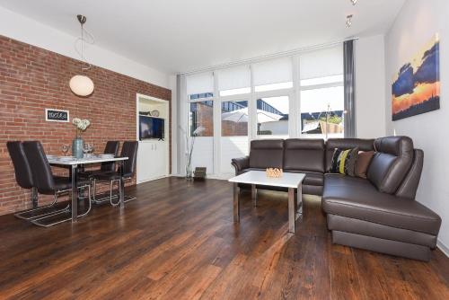 a living room with a leather couch and a table at Ferienwohnungen MARENOR in Bensersiel