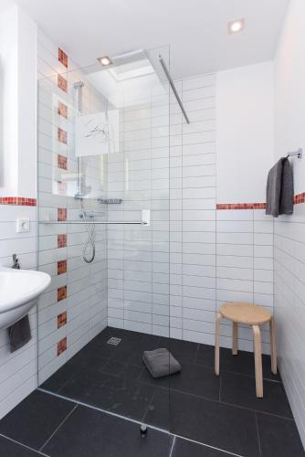 a white bathroom with a sink and a stool at Ferienwohnungen MARENOR in Bensersiel