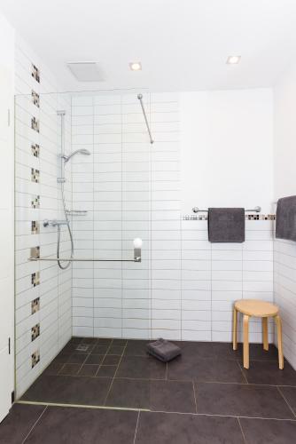 a bathroom with a shower and a wooden stool at Ferienwohnungen MARENOR in Bensersiel