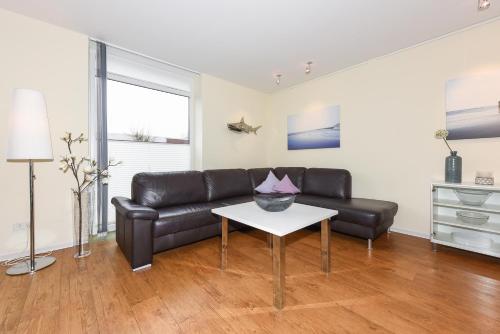 a living room with a leather couch and a table at Ferienwohnungen MARENOR in Bensersiel