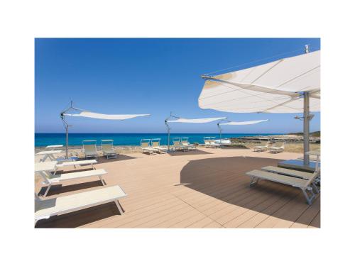 un grupo de sillas y sombrillas en una playa en Grand Hotel Masseria Santa Lucia, en Ostuni