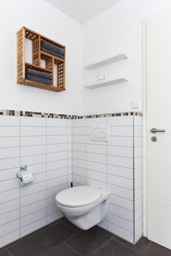 a white bathroom with a toilet and a mirror at Ferienwohnungen MARENOR in Bensersiel