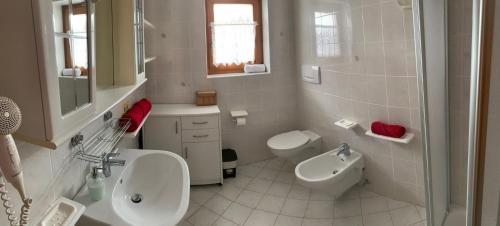 a white bathroom with a sink and a toilet at Bachlaufen Haus in Sesto