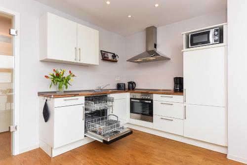 a kitchen with white cabinets and a dishwasher at Ferienwohnungen MARENOR in Bensersiel