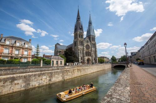 a group of people in a boat on a river with a church at Camping de Châlons-en-Champagne in Châlons-en-Champagne