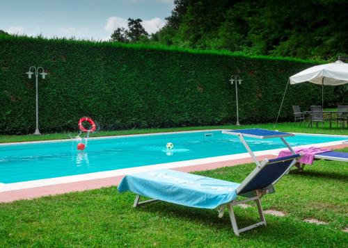 a swimming pool with a chair and an umbrella at Agriturismo Tenuta Adamo in Lucca
