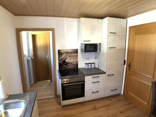 a kitchen with a stove and a microwave at Gästehaus Berger inkl. Chiemgaukarte in Ruhpolding