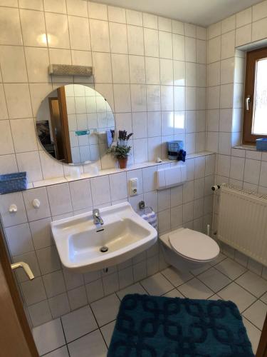 a bathroom with a sink and a toilet and a mirror at Gästehaus Berger inkl. Chiemgaukarte in Ruhpolding