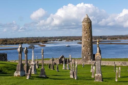 an old stone tower in a field next to a body of water at Tullamore Court Hotel in Tullamore