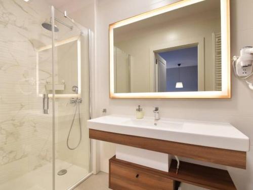 y baño con lavabo y ducha con espejo. en Apartament 403D Bel Mare Międzyzdroje, en Międzyzdroje