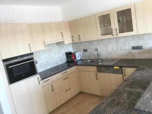 a kitchen with white cabinets and a sink at Panoramisch appartement tussen zee ,bos en de duinen in De Panne