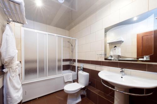 La salle de bains est pourvue de toilettes, d'un lavabo et d'un miroir. dans l'établissement Noviy Otel, à Smolensk