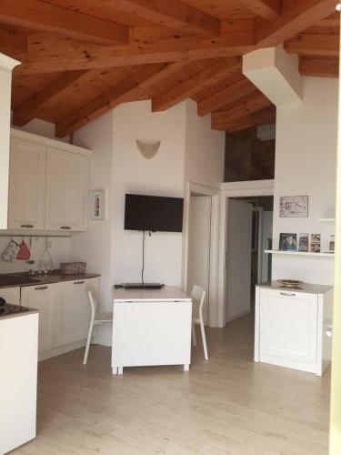 タヴェルノラ・ベルガマスカにあるBalcone sul lagoの白いキャビネットと薄型テレビ付きのキッチンが備わります。