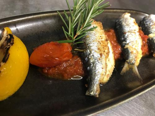 a black plate of food with fish and other foods at Auberge le Montana in Saint-Florent