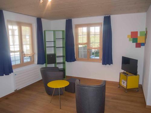 a living room with blue curtains and a table and chairs at Studio Zentrum EG in Adelboden