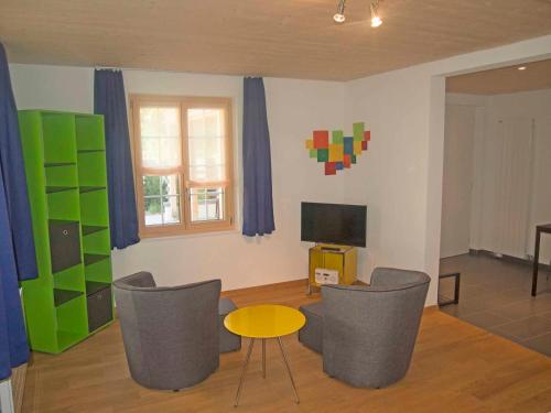 ein Wohnzimmer mit Stühlen, einem Tisch und einem TV in der Unterkunft Studio Zentrum EG in Adelboden