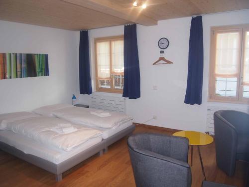 a bedroom with a bed and a chair and blue curtains at Studio Zentrum EG in Adelboden
