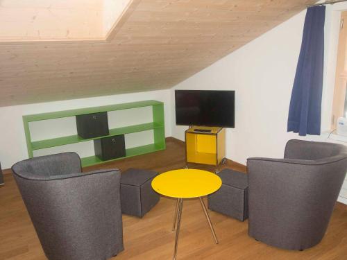 un soggiorno con tavolo, sedie e TV di Studio Zentrum OG ad Adelboden