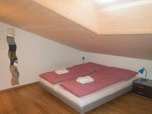 ein Schlafzimmer mit einem roten Bett im Dachgeschoss in der Unterkunft Studio Zentrum OG in Adelboden