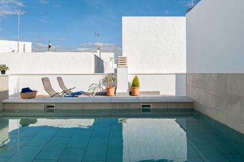 a swimming pool with two chairs next to a building at Apartamentos Wamba in Conil de la Frontera