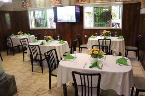 a dining room with tables and chairs with flowers on them at United Hotel in Mbankomo