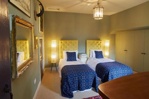 a bedroom with two beds with blue comforters and a mirror at The Tower Rooms in Fakenham