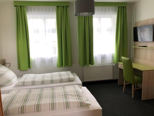 Habitación de hotel con 2 camas, escritorio y cortinas verdes en Burghotel Homberg, en Homberg