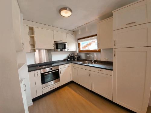 a kitchen with white cabinets and a sink at Walensee House & Apartments in Unterterzen