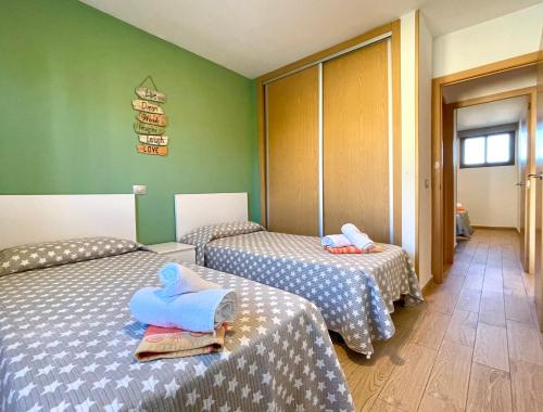 two beds in a room with green walls at OHMYHOST360 - Sunny Home Holidays in Playa del Ingles