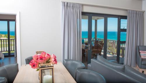 a dining room with a table and a view of the ocean at Brenton Haven Beachfront Resort in Knysna