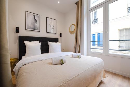 une chambre avec deux lits et une grande fenêtre dans l'établissement MBM - Marais, à Paris