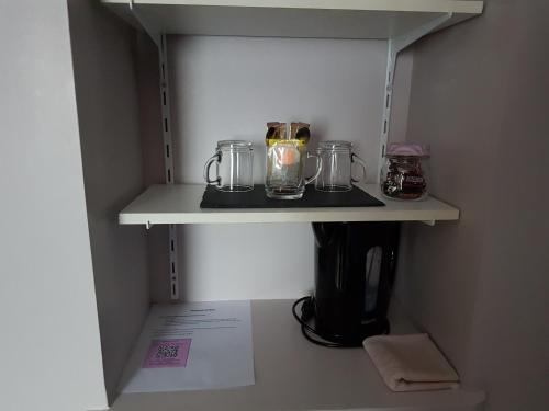 a shelf in a cupboard with three glass jars at Chambre Rose à la Campagne 