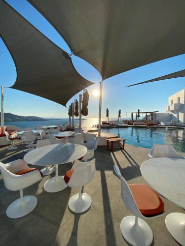 a group of tables and chairs next to a pool at Absolute Mykonos Suites & More in Mikonos