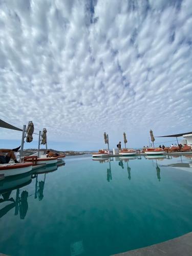 a pool of water with people laying on the chairs at Absolute Mykonos Suites & More in Mikonos