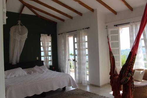 een slaapkamer met een wit bed en een aantal ramen bij Casa con piscina y zona de BBQ en la Mesa Cundinamarca in Anapoima