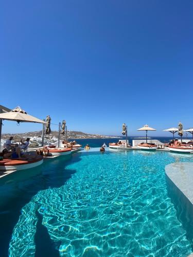 a swimming pool with umbrellas and the ocean in the background at Absolute Mykonos Suites & More in Mikonos