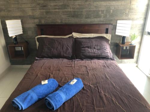1 cama con 2 almohadas azules y 2 lámparas en B and B Marcos Paz Apartment en San Miguel de Tucumán