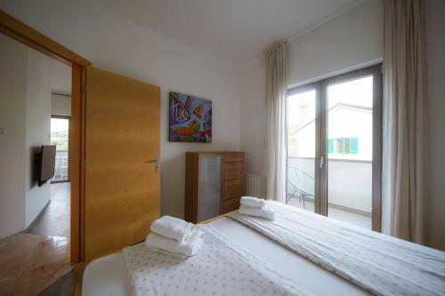 1 Schlafzimmer mit 2 weißen Betten und einer Glasschiebetür in der Unterkunft Villa Medusa in Lucija