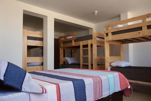 a bedroom with bunk beds and a bed with a striped blanket at Hotel Munay in Paracas