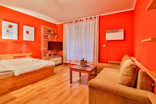 a bedroom with orange walls and a bed and a couch at Apartmánový dom Fatrapark 1 s Wellness - Hlavná recepcia in Ružomberok