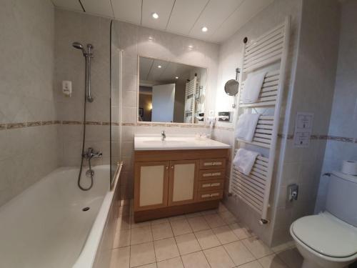 a bathroom with a tub and a sink and a toilet at Le Chalet Suisse in Valberg