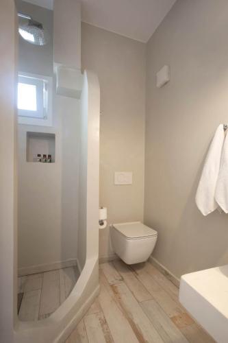 a white bathroom with a toilet and a sink at Kouros Village in Antiparos Town